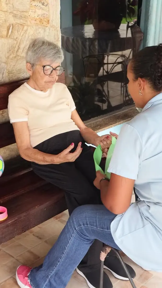Profissional de enfermagem atende uma idosa sentada