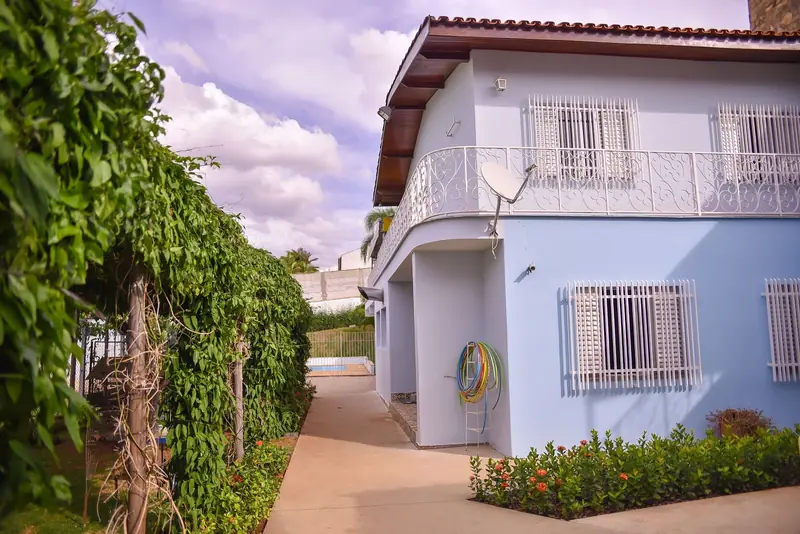 Fachada da casa coberta por trepadeiras, com o jardim na frente